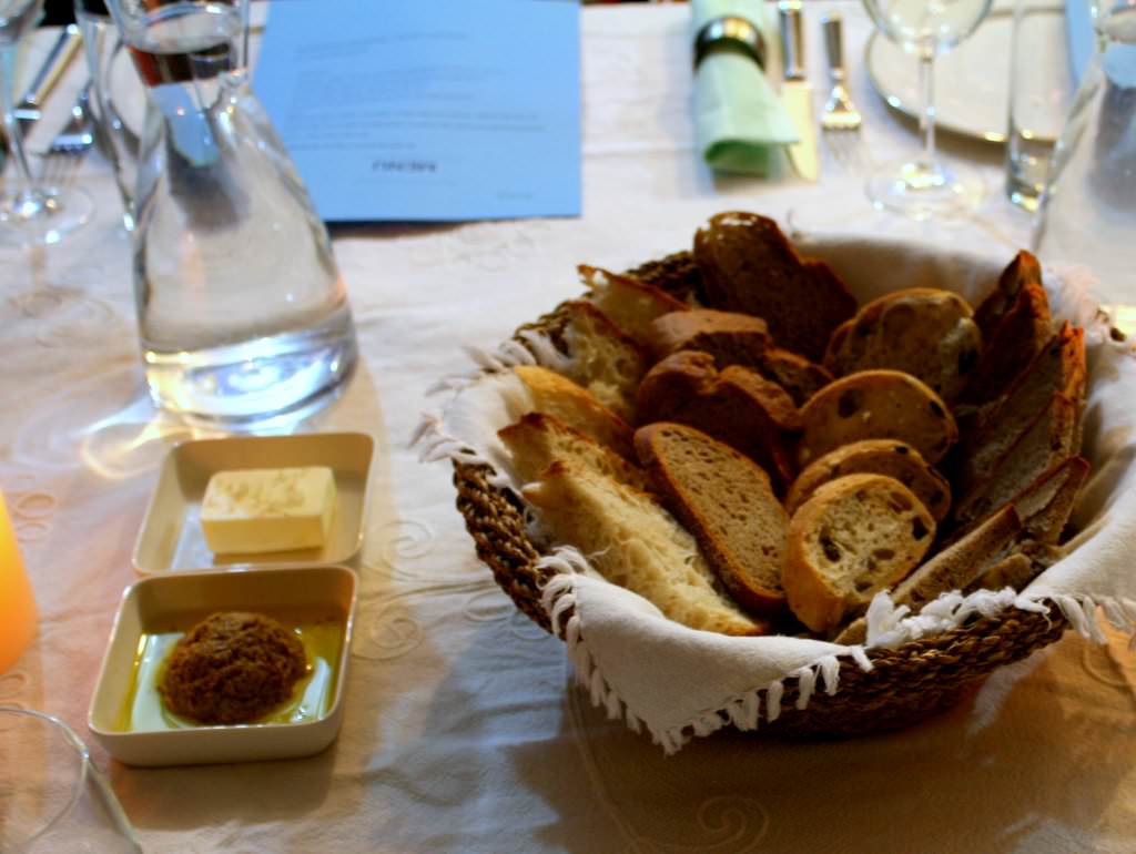 Four types of bread: Olives bread, Rustic bread, white French bread and walnut bread , with green olives tapenade and butter.