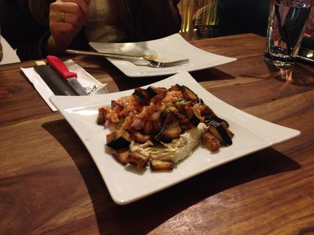 Salmon tartare and baked eggplant served on a bed of almond tehini, garnished with radish, hot pepper.