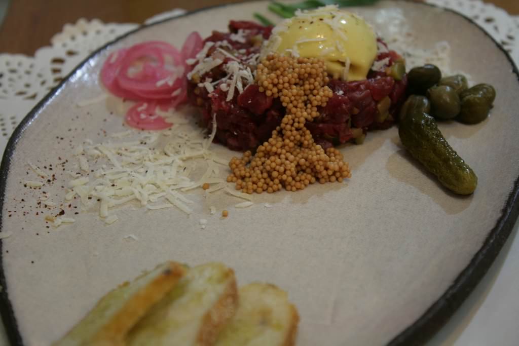 Classic - modern: Steak Tartare coarsely cut with a knife, capers, pickled onions, yolks and mustard ice cream, pickled mustard seeds, cornichon, parmesan and paprika. Served with crispy toast.